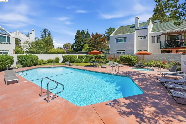 In-ground swimming pool with integrated spa, surrounded by a concrete patio and lush landscaping