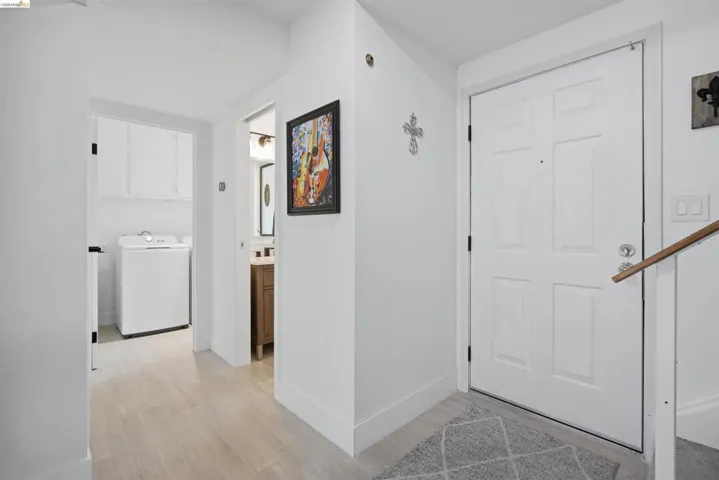 Entryway featuring a paneled door, wood-finish flooring, and a wooden handrail
