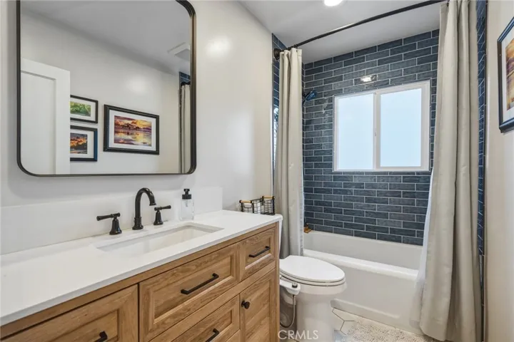 Updated bathroom with hexagonal tile flooring, oversized vanity and floor-to-ceiling subway tile
