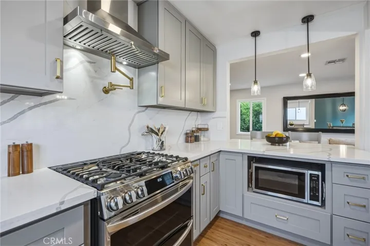 Chef’s kitchen with solid quartz counters, slab backsplash to the ceiling, pot filler, LG stainless package with double oven, and custom cabinets/drawers