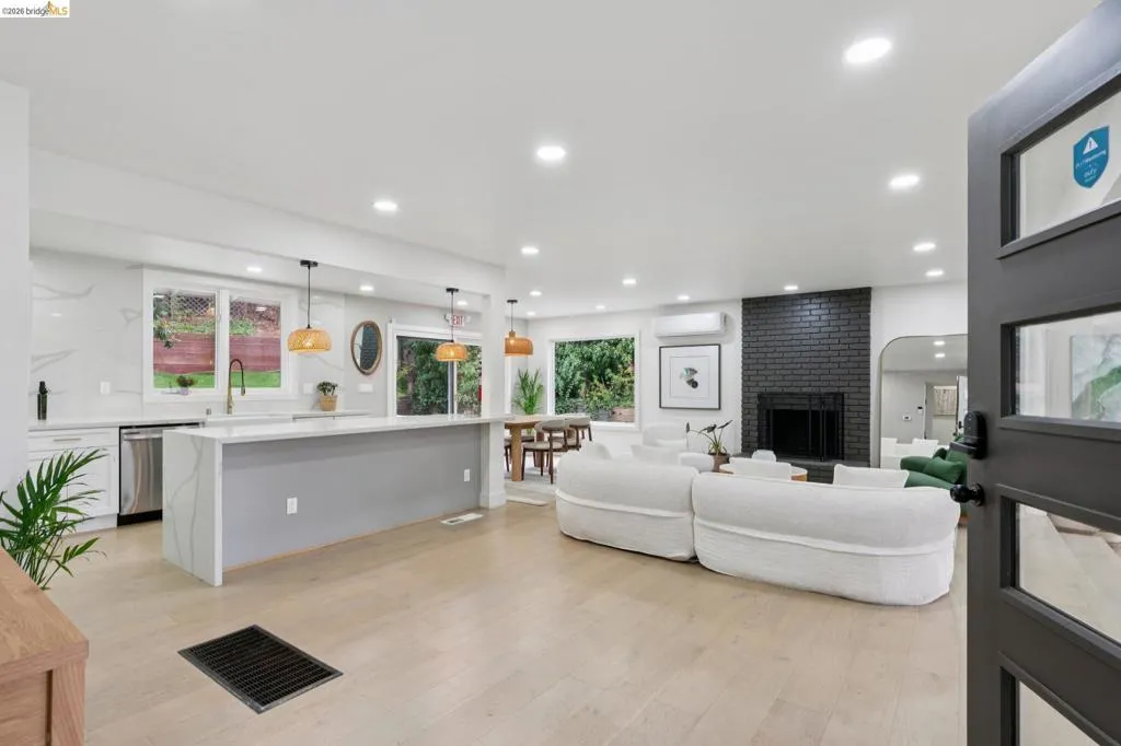 Open-concept living space featuring wood-finish flooring, recessed lighting, and a black brick fireplace