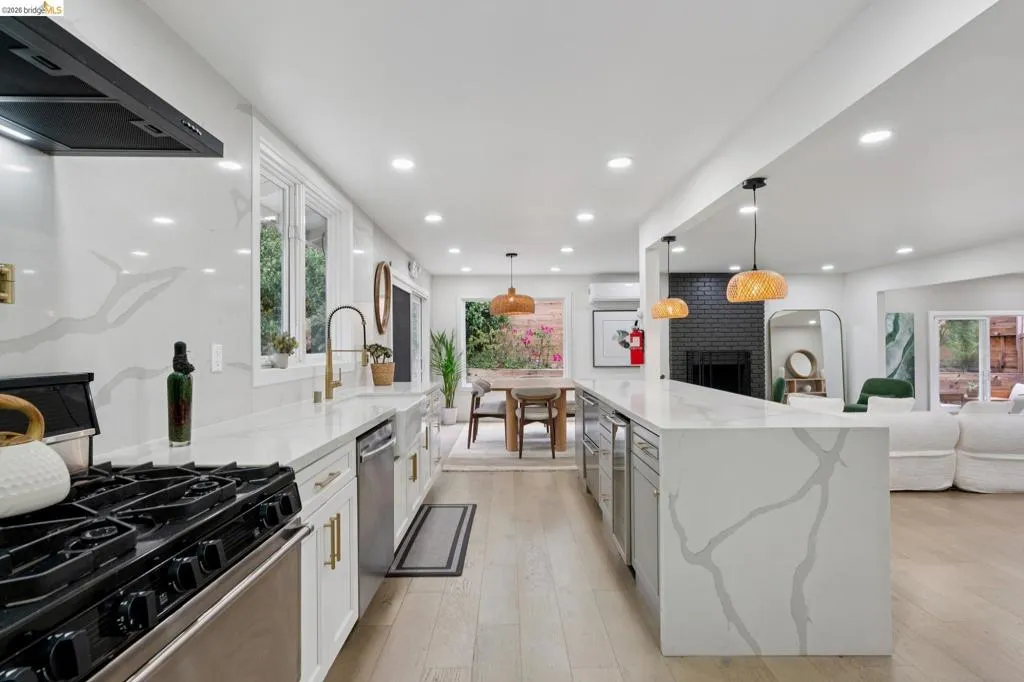 Spacious kitchen featuring an extended island with a waterfall edge, integrated beverage refrigerators, and recessed lighting