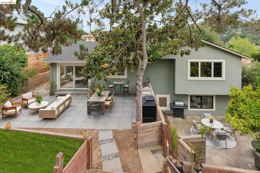 Expansive patio area featuring large format pavers, an exterior sliding glass door, and multiple levels of outdoor space