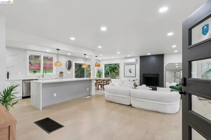 Open-concept living space featuring wood-finish flooring, recessed lighting, and a black brick fireplace