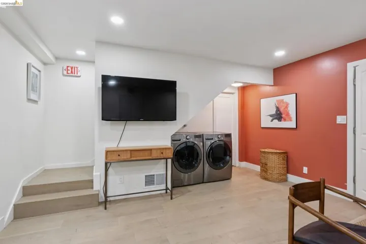 Spacious lower level featuring wood-finish flooring, recessed lighting, and a dedicated laundry area with stacked appliances