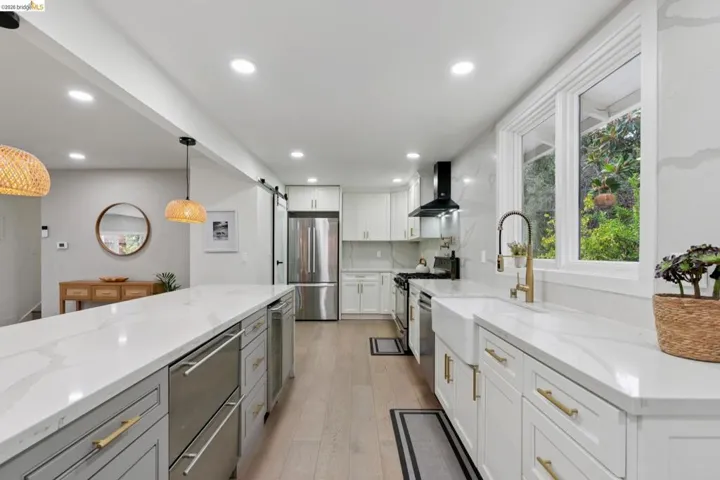 Modern kitchen featuring a large center island, stainless steel appliances, white cabinetry, and wood-finish flooring