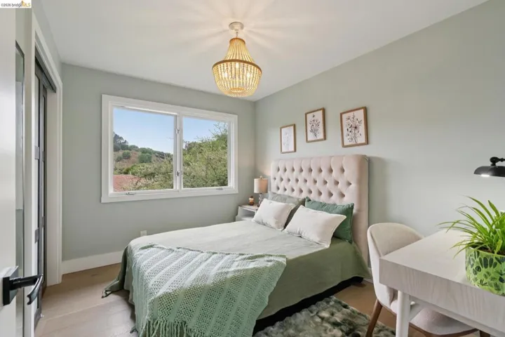 Light-filled room featuring wood-finish flooring, a contemporary chandelier, a window with outdoor scenery, and a paneled door with dark hardware