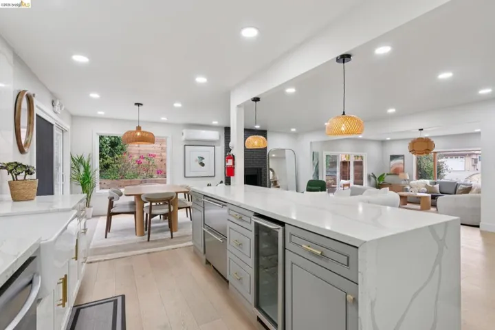 Expansive kitchen island featuring a waterfall countertop with integrated wine refrigerator and dishwasher