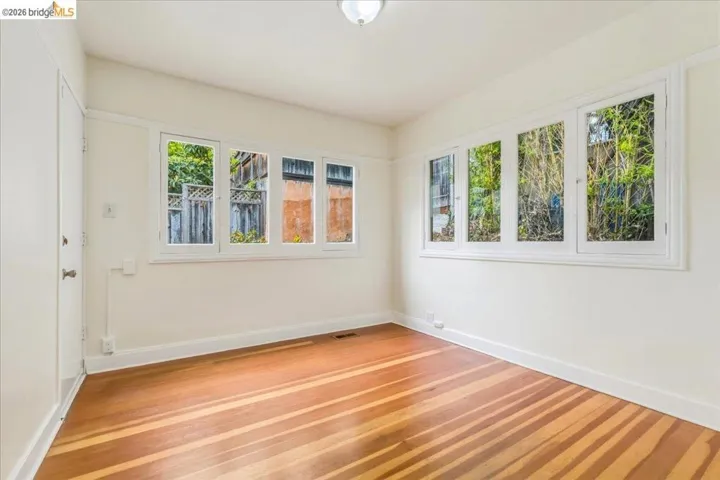 Hardwood flooring throughout, white baseboards, and multiple windows with white trim