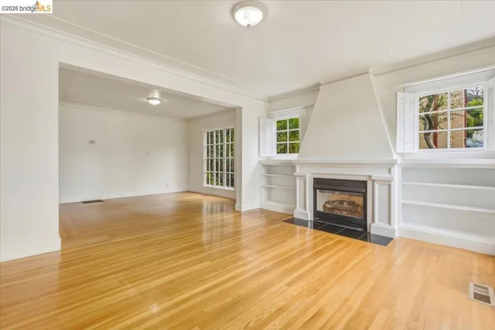Living room featuring wood-finish flooring, a fireplace with a black tile hearth, and built-in shelving
