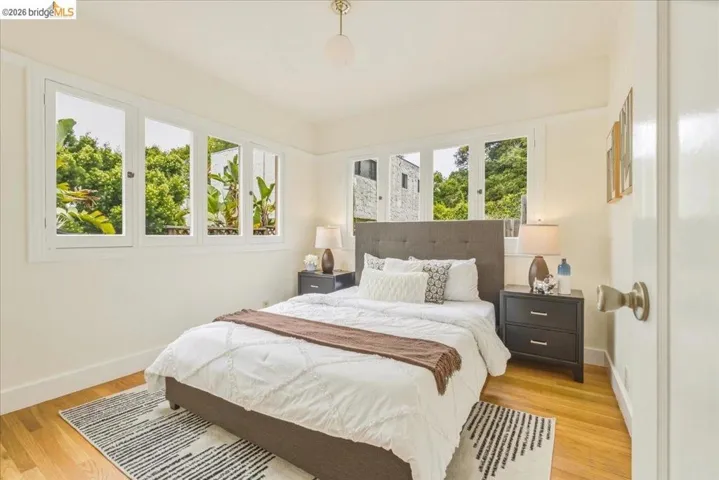 Bedroom featuring hardwood flooring, white baseboards, and a series of white-framed windows