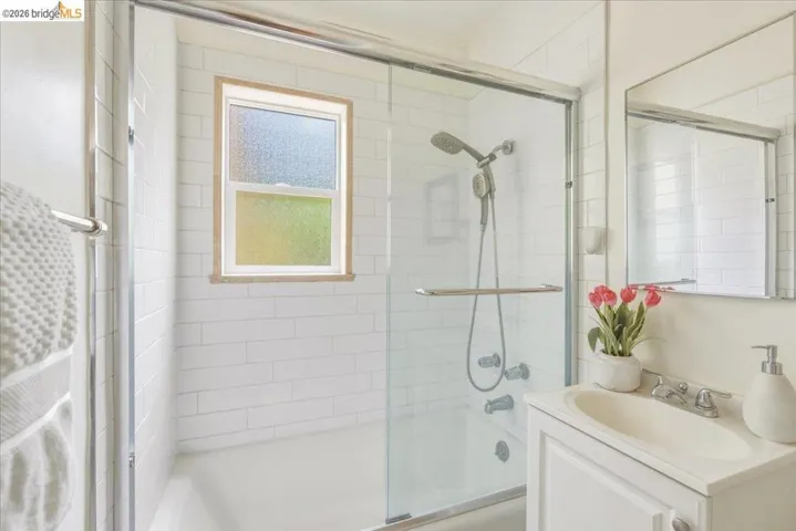 Bathroom featuring a tub/shower combination with white subway tile surround and a sliding glass enclosure
