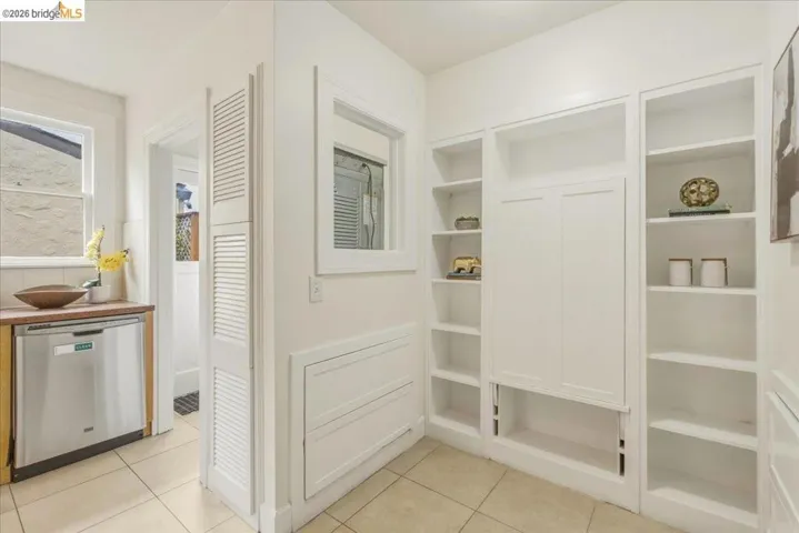 Built-in shelving and cabinetry offer extensive storage, complemented by a stainless steel dishwasher and a wood-finish countertop
