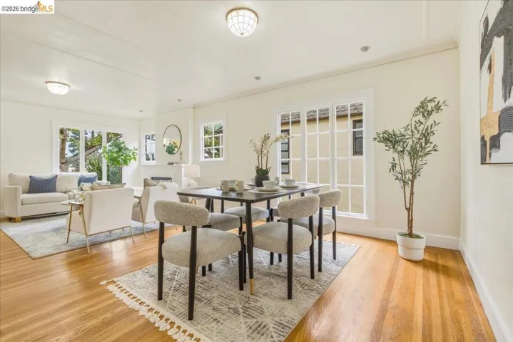 Expansive living and dining areas featuring warm wood-finish flooring, white trim, and multiple large windows
