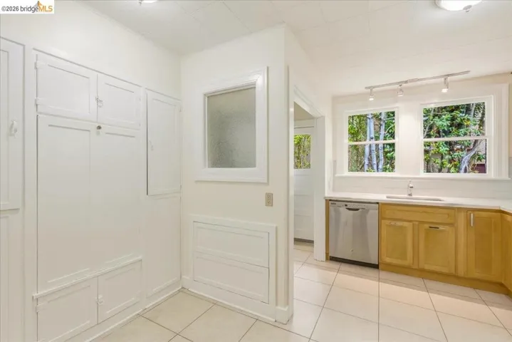 Kitchen featuring light wood cabinetry, a stainless steel dishwasher, and a single-basin sink with a chrome faucet