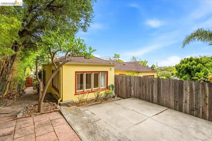 Rear exterior featuring a yellow stucco finish and a brown shingle roof