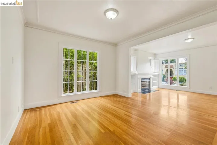 Spacious room featuring wood-finish flooring, white walls, and bright overhead lighting