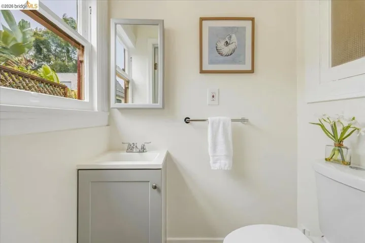 Bathroom with a single-pane window, white walls, and a gray vanity with an integrated sink