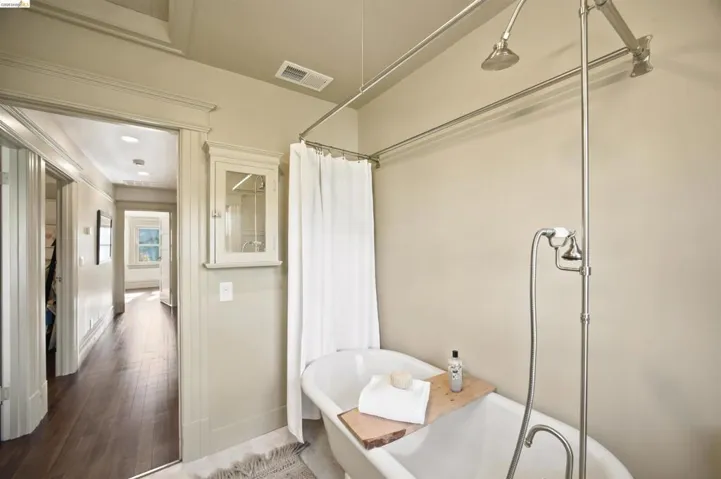 Clawfoot tub with polished nickel fixtures, including a handheld shower and rainfall showerhead