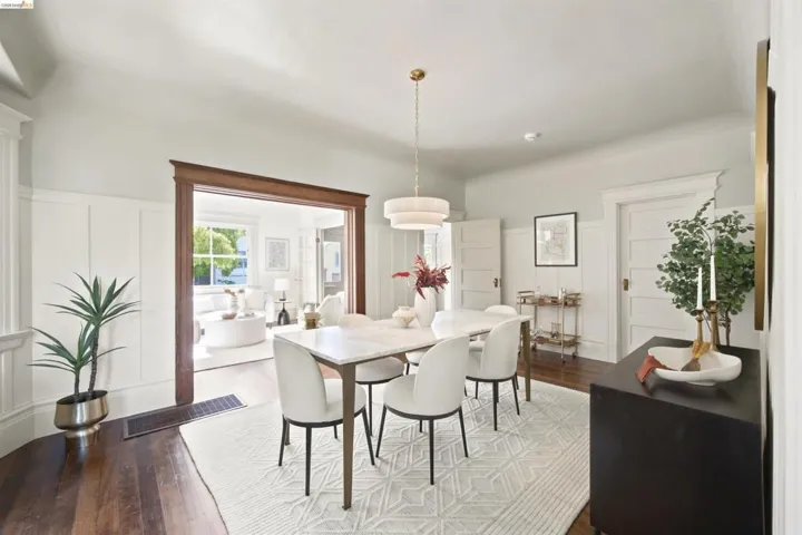 Hardwood flooring extends throughout this dining area, featuring wainscoting and a wide cased opening to an additional room