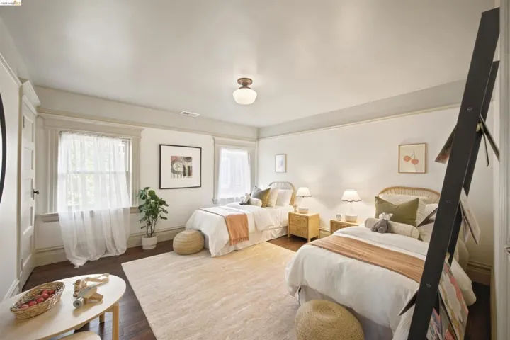 Spacious room featuring rich wood-finish flooring, multiple windows providing ample natural light, and a light-colored area rug