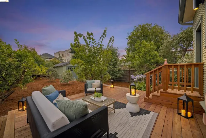 Expansive wood deck with a built-in staircase and railing, surrounded by mature trees and landscaping