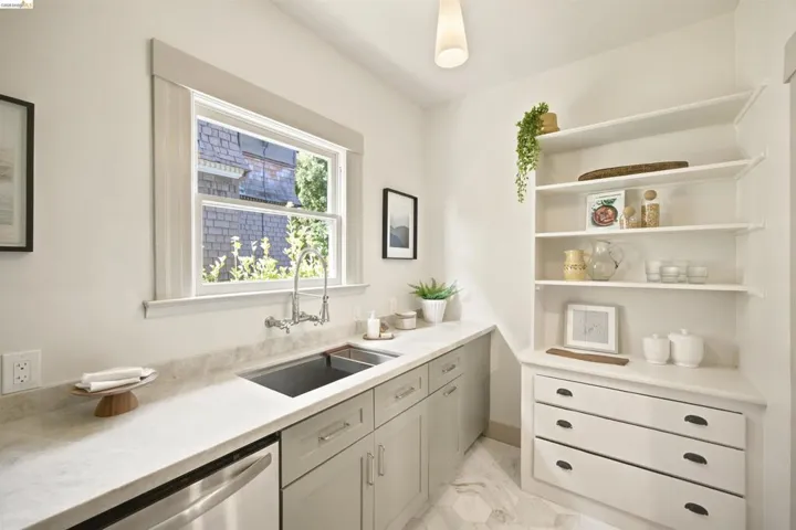 Kitchenette featuring light-colored cabinetry, stainless steel sink with a wall-mounted faucet, and light-toned countertops