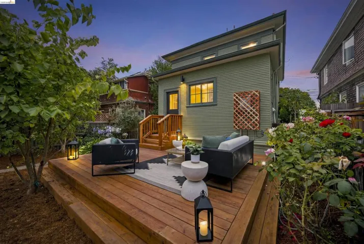 Tiered wood deck with integrated steps, featuring a wood lattice panel, a rear entry door, and exterior sconce lighting