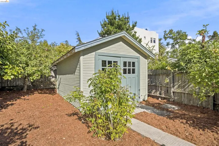 Detached shed with light-colored siding and a pitched roof
