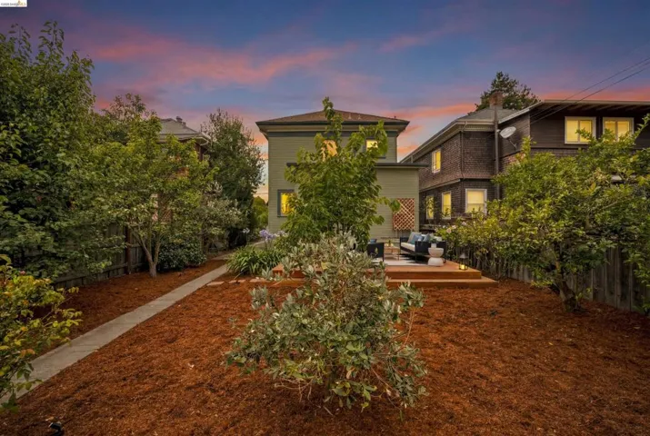 Expansive backyard featuring a tiered wood deck, mulched landscaping, and mature trees