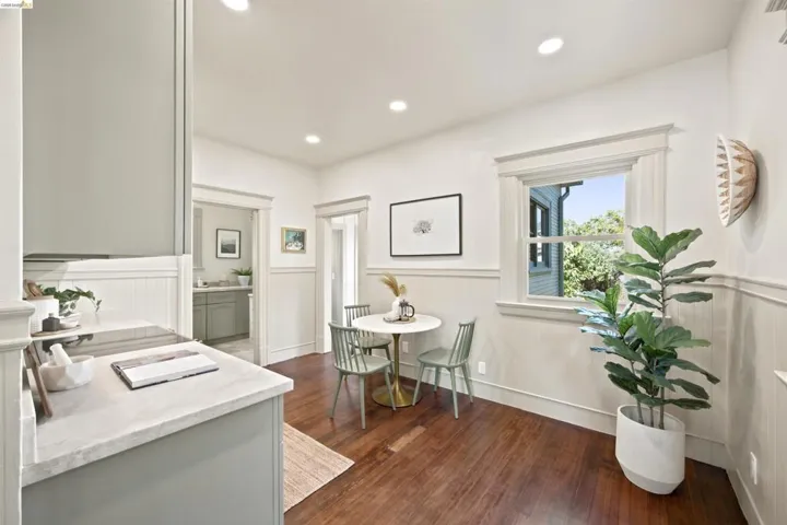 Hardwood-style flooring and white wainscoting highlight this bright dining area, featuring a double-hung window with decorative trim