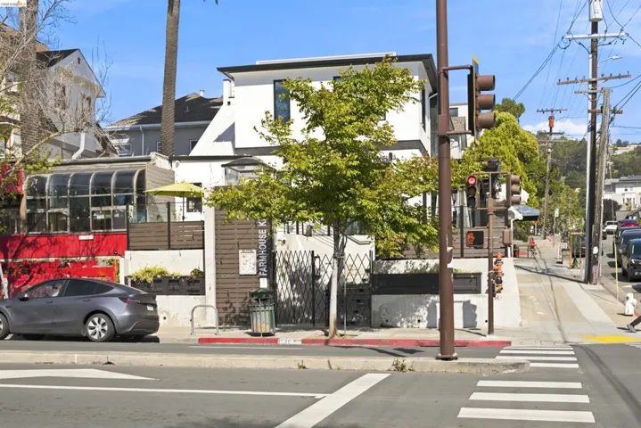 Modern multi-story building featuring a white facade with dark trim, a prominent front entrance, and a sloped roofline