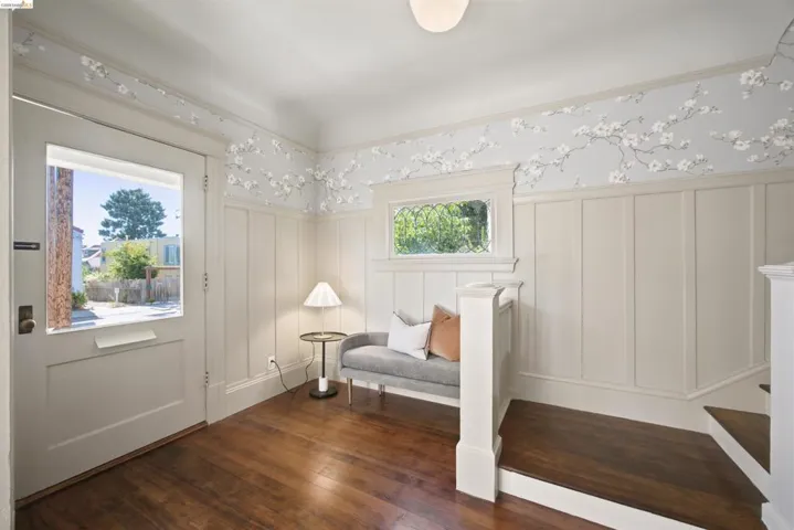 Entryway featuring hardwood flooring, wainscoting, an ornate window, and a glass-paneled entry door