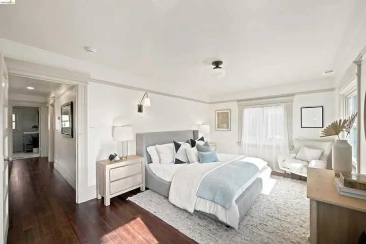 Spacious room featuring rich wood-finish flooring, a contemporary ceiling light fixture, and a large window with sheer coverings