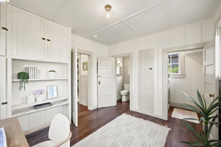 White paneled walls and dark wood-finish flooring create a bright ambiance, complemented by built-in shelving and cabinetry