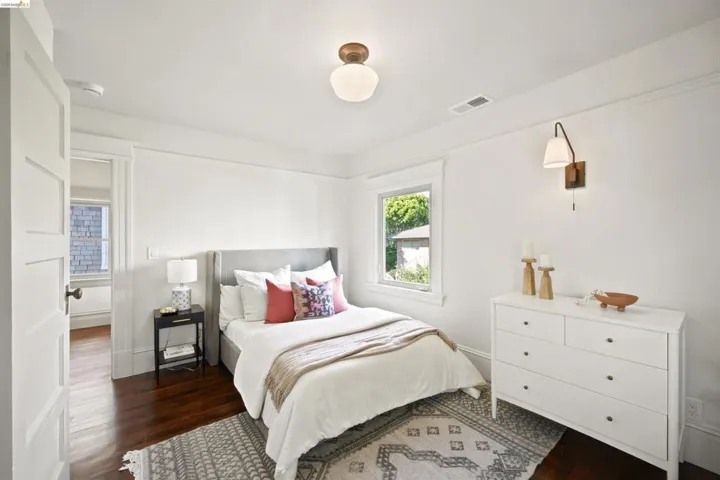 Bedroom featuring rich wood-finish flooring, white trim, and a window with exterior views