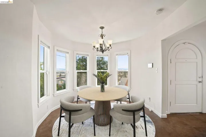 Bay window area featuring multiple double-hung windows, a five-light chandelier, an arched doorway, and wood-finish flooring