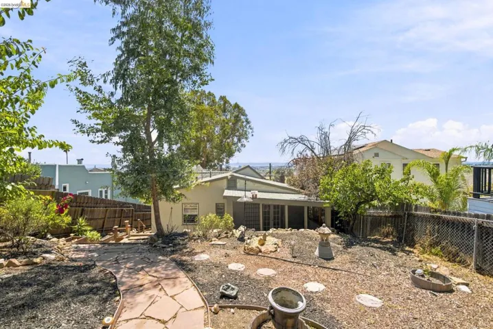 Expansive backyard featuring a winding flagstone pathway, mature trees, and a wooden privacy fence