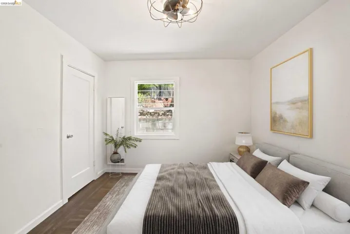 Bedroom featuring wood-finish flooring, white walls, a single window, and a modern ceiling fixture