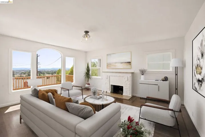 Spacious living area featuring large picture windows, a prominent arched window, wood-finish flooring, and a decorative fireplace