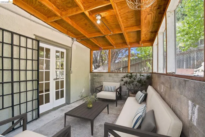 Outdoor patio featuring a wood-beam ceiling, concrete flooring, and multiple glass panels