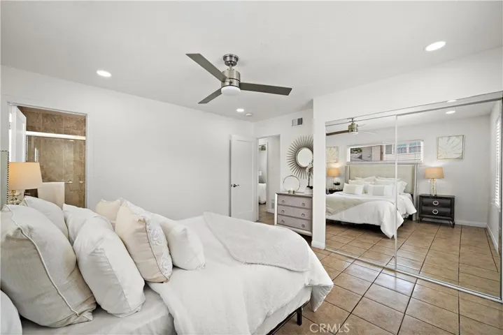 Primary suite downstairs with mirrored closet, title flooring, recessed lighting, ceiling fan, and ensuite bathroom