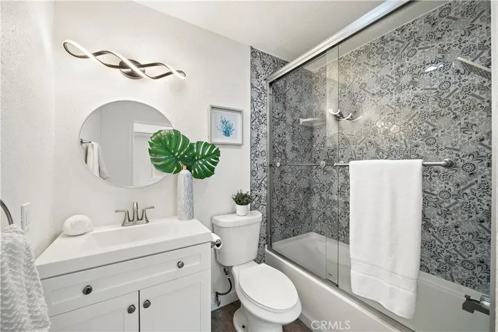 Downstairs guest bathroom with tub/shower combo, tile surround, clear glass enclosure