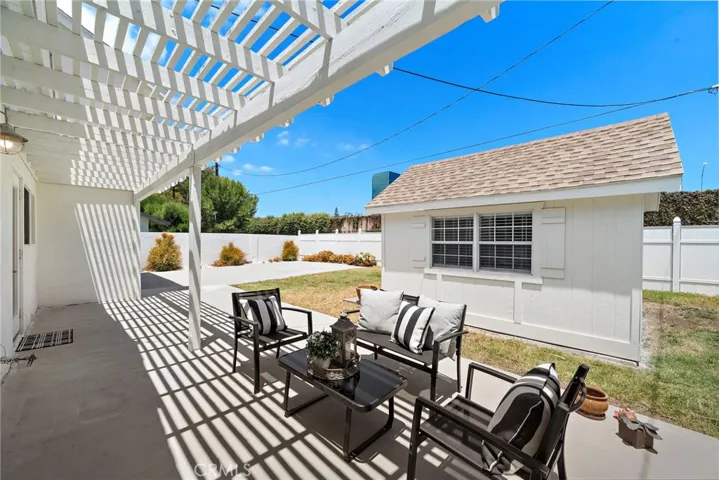 Backyard with covered patio, vinyl fencing, lawn, custom shed with electricity