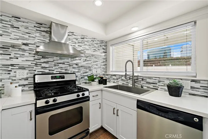 Quartz countertops, glass mosaic title backsplash, floating open shelving