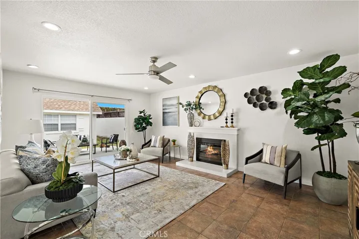 Spacious living room with fireplace, recessed lighting, title flooring, and slider leading to backyard