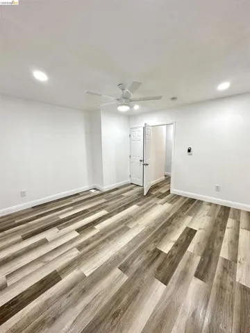 Spacious interior featuring multi-toned wood-finish flooring, recessed lighting, and a contemporary ceiling fan