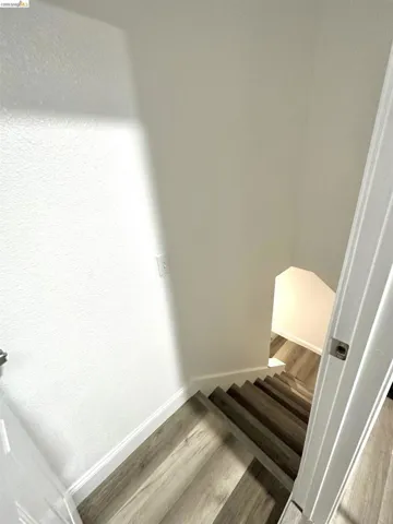 Stairwell featuring wood-finish treads, crisp white risers, and white baseboards