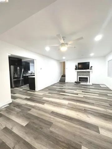 Spacious living area featuring wood-finish flooring, a contemporary ceiling fan, and recessed lighting