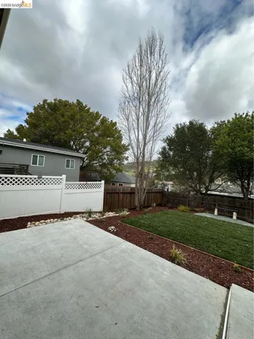 Expansive concrete patio area with a manicured lawn and surrounding mulch beds